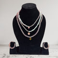 Handmade Trinkets layered necklace with pink heart, flower, and N charm, paired with crystal bead hoop earrings. Pink and iridescent aurora finish.